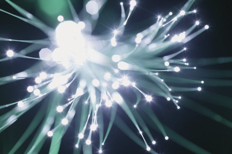 speed of light Abstract close-up of glowing fiber optic strands against a dark background.